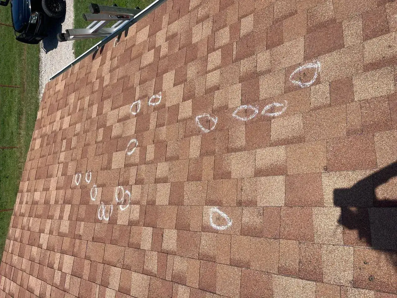 Chalk circles marking hail impacts on brown asphalt shingles