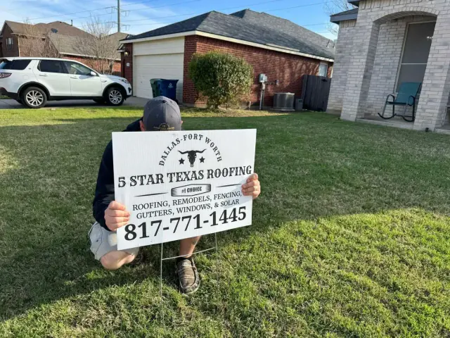 Person holding a sign for "5 Star Texas Roofing" in a yard; house and car in background.