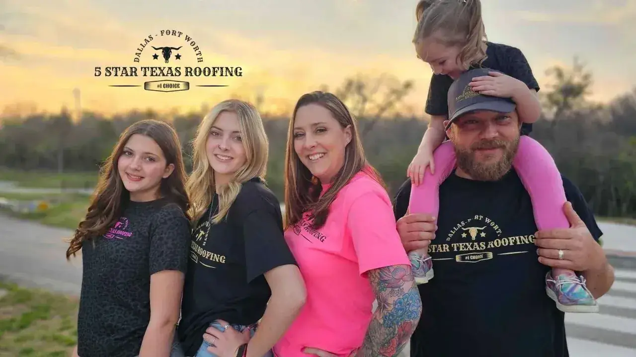 Family of five smiling, two daughters, mom, and dad with child on shoulders, outdoors.